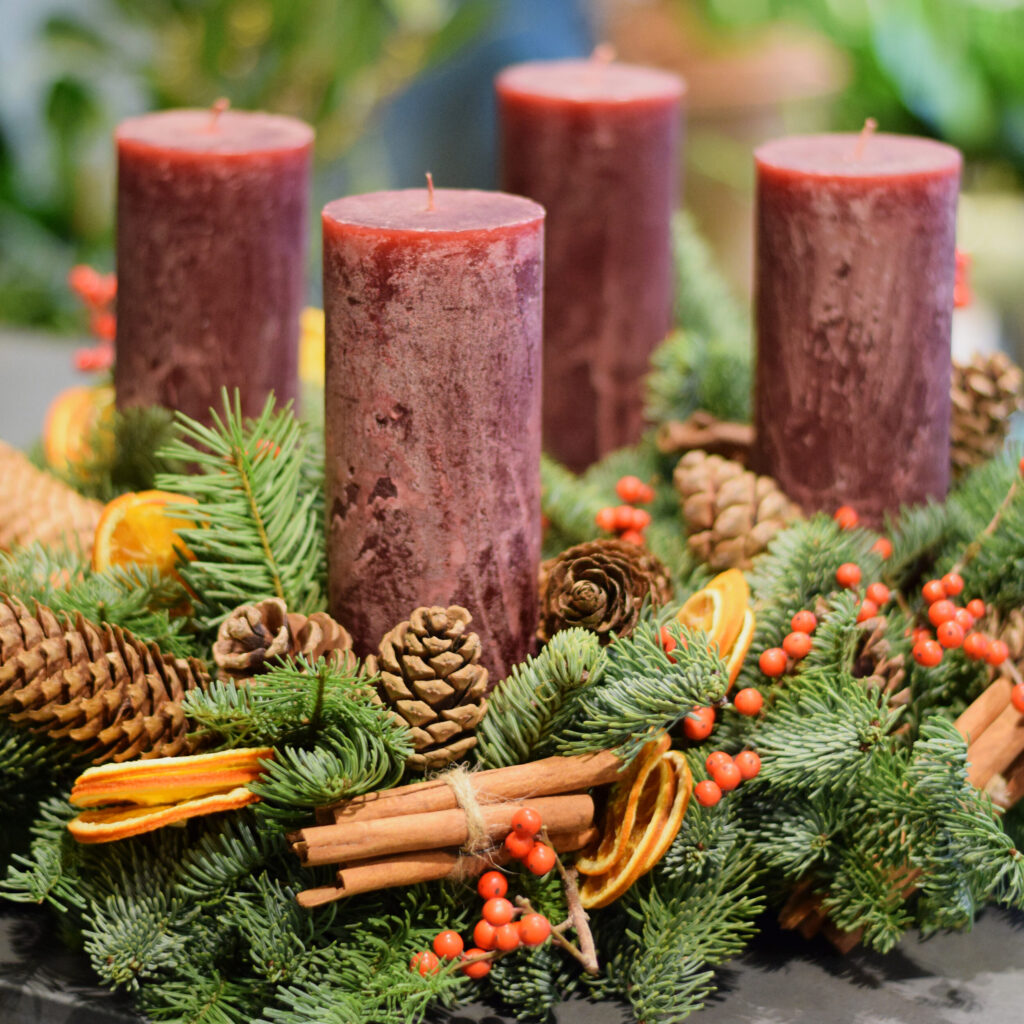 Sample of a luxury Advent wreath, pine, ilex red berry, orange fruits, cones and cinnamon available to order from Kensington flowers London