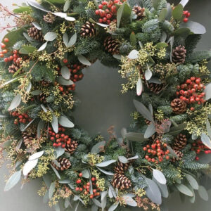 Photo showing a sample of The Elizabeth Christmas door wreath a pine and mix festive foliage door wreath available to order from Kensington flowers London