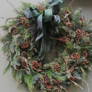 Photo showing a sample of The Charles Christmas wreath, made of fresh mixed pines, cones and lichen textures, available to order from Kensington flowers London