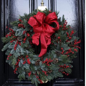 Photo showing a sample of The Luxury Albert Christmas door wreath, a fresh pine and red berry wreath available to order from Kensington Flowers London