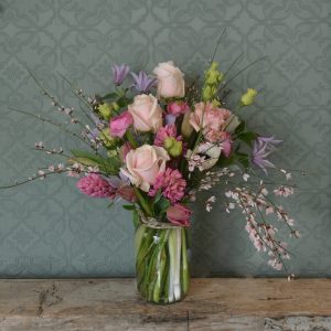 Photo showing a sample of a Mother's Day jar of flowers, a large jam jar filled with pastel flowers in pink and lilac colours, including roses and scented hyacinths. Available to order from Kensington Flowers London